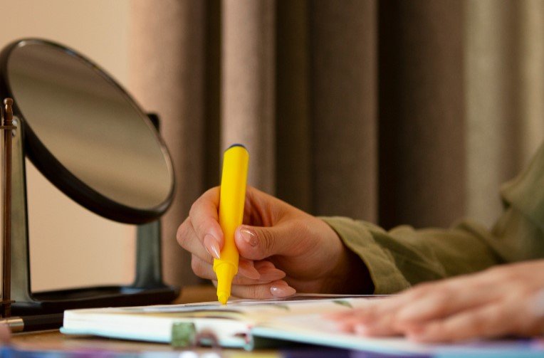 Students Study Tips - Student Highlighting Notes with Yellow Marker in Open Book